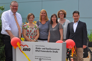 Eine Gruppe steht hinter einem Schild mit der Aufschrift AWO-Kinder- und Familienzentrum Fremersdorfer Straße