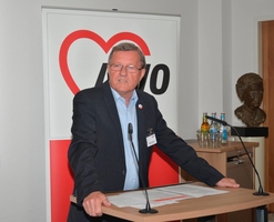 Wilhelm Schmidt steht am Rednerpult. Im Hintergrund ist das AWO-Logo zu sehen.