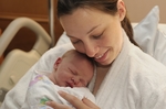 Eine Mutter im Krankenhausbett mit Säugling im Arm