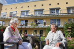 Zwei Bewohnerinnen sitzen auf Gartenmöbeln in einem Garten vor dem Wohn- und Pflegeheim Am Eikel.