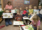 Eine Erzieherin und Kinder lesen in Büchern