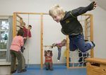 Kinder springen und klettern im Sportunterricht unter Aufsicht einer Erzieherin