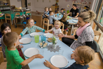 Kinder und Betreuer sitzen beim Essen an Tischen.