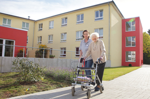 Eine Bewohnerin und eine Pflegerin gehen vor dem Wohn- und Pflegeheim Krugwiese spazieren